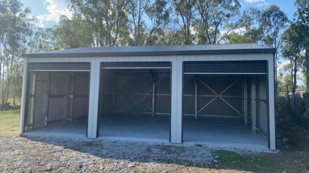 A Garage With Three Doors Is Sitting In The Middle Of A Dirt Field — Just Sheds In Kunda Park, QLD