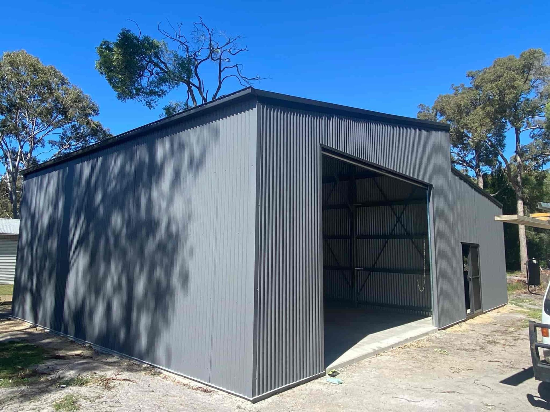 A Large Gray Metal Building With A Large Sliding Door — Just Sheds In Kunda Park, QLD