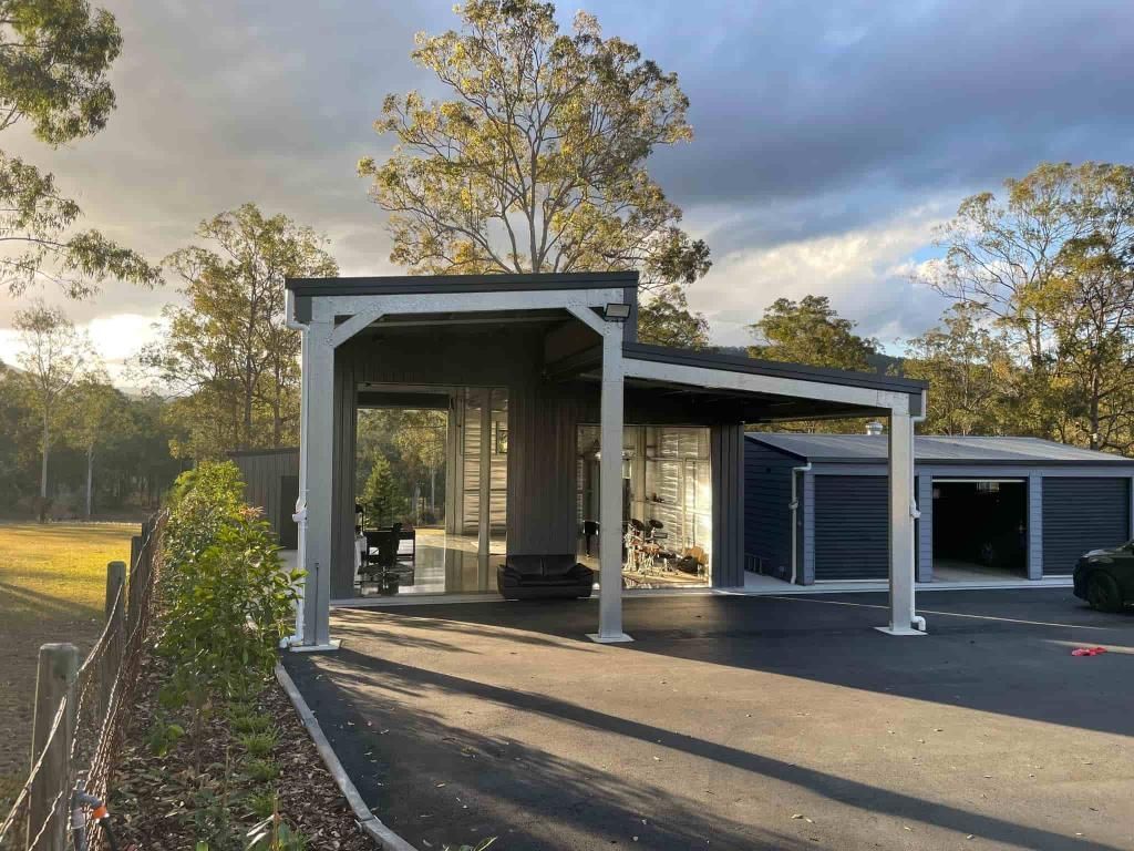 A House With A Carport And A Garage Is Surrounded By Trees And A Fence — Just Sheds In Kunda Park, QLD