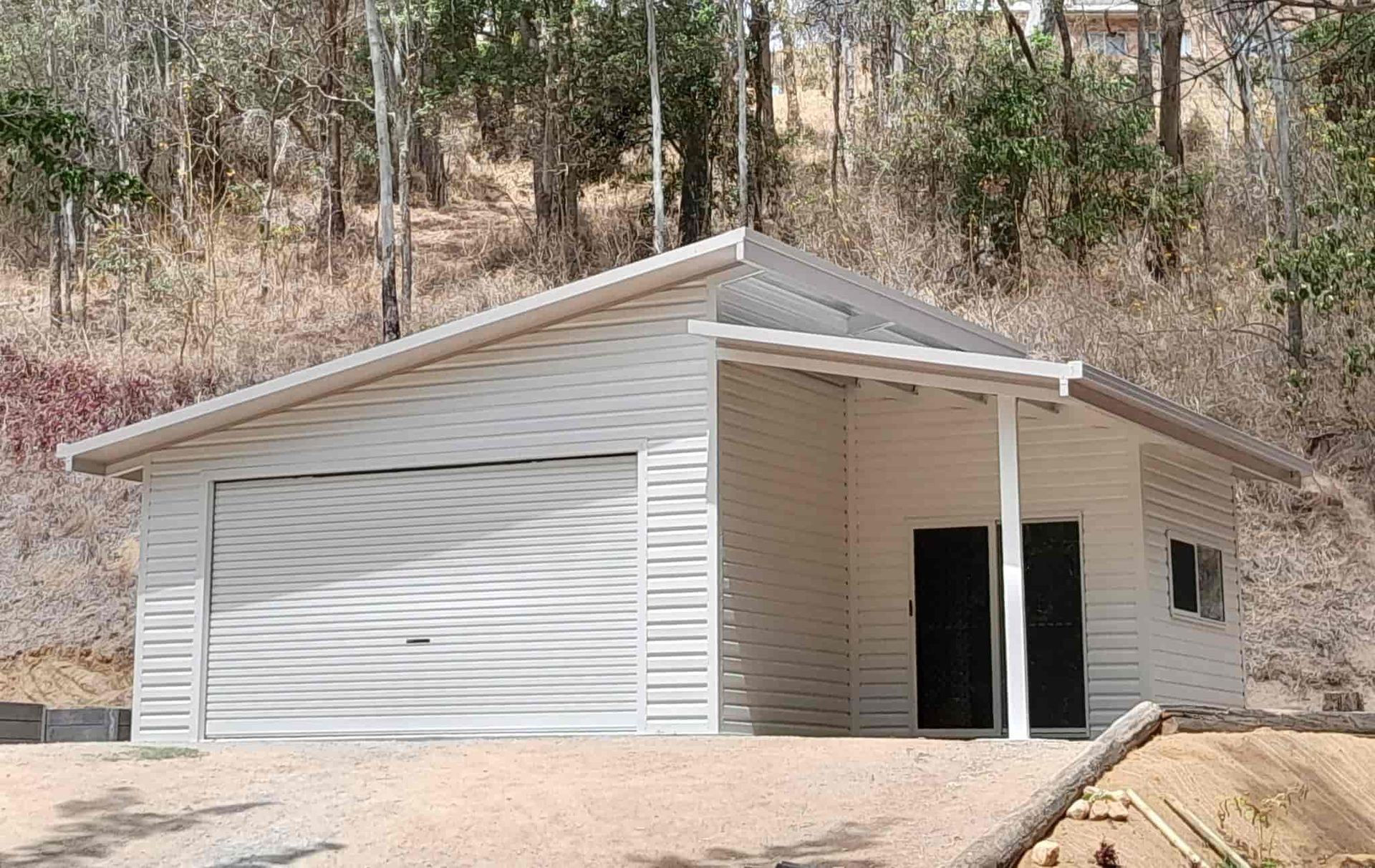 A White Garage With A Covered Porch Is Sitting On Top Of A Dirt Hill — Just Sheds In Kunda Park, QLD