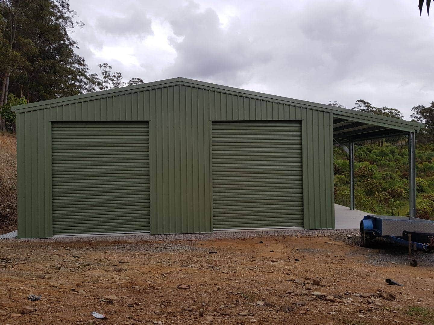 A green metal garage with two garage doors and a canopy. — Just Sheds In Kunda Park, QLD