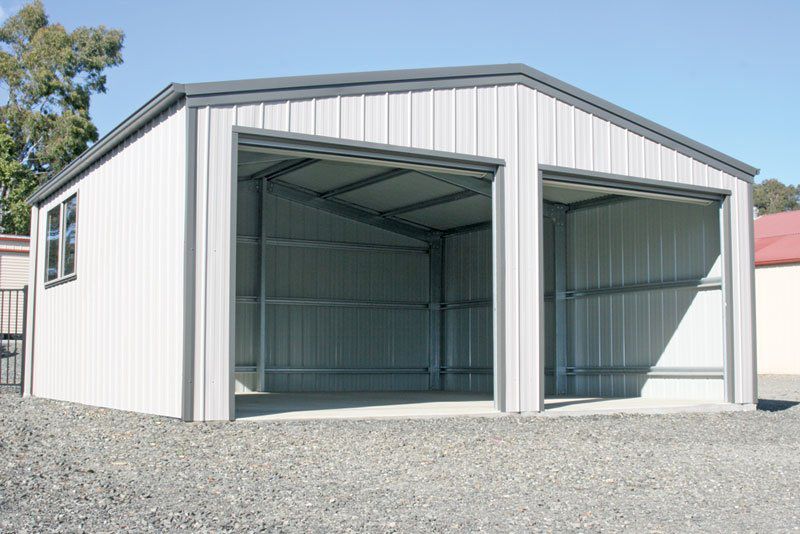 A Green Barn With a Tan Door is in the Middle of a Grassy Field — Just Sheds In Kunda Park, QLD