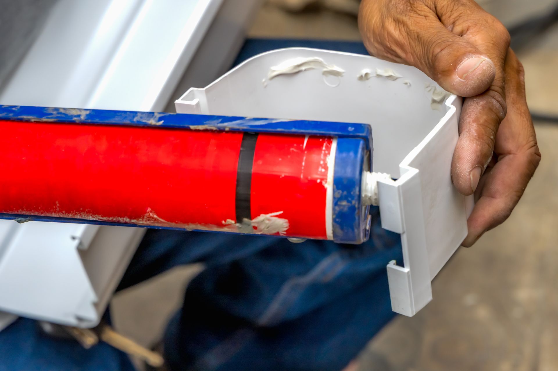Hand installing a red pipe into a gray plastic fitting with a blue collar