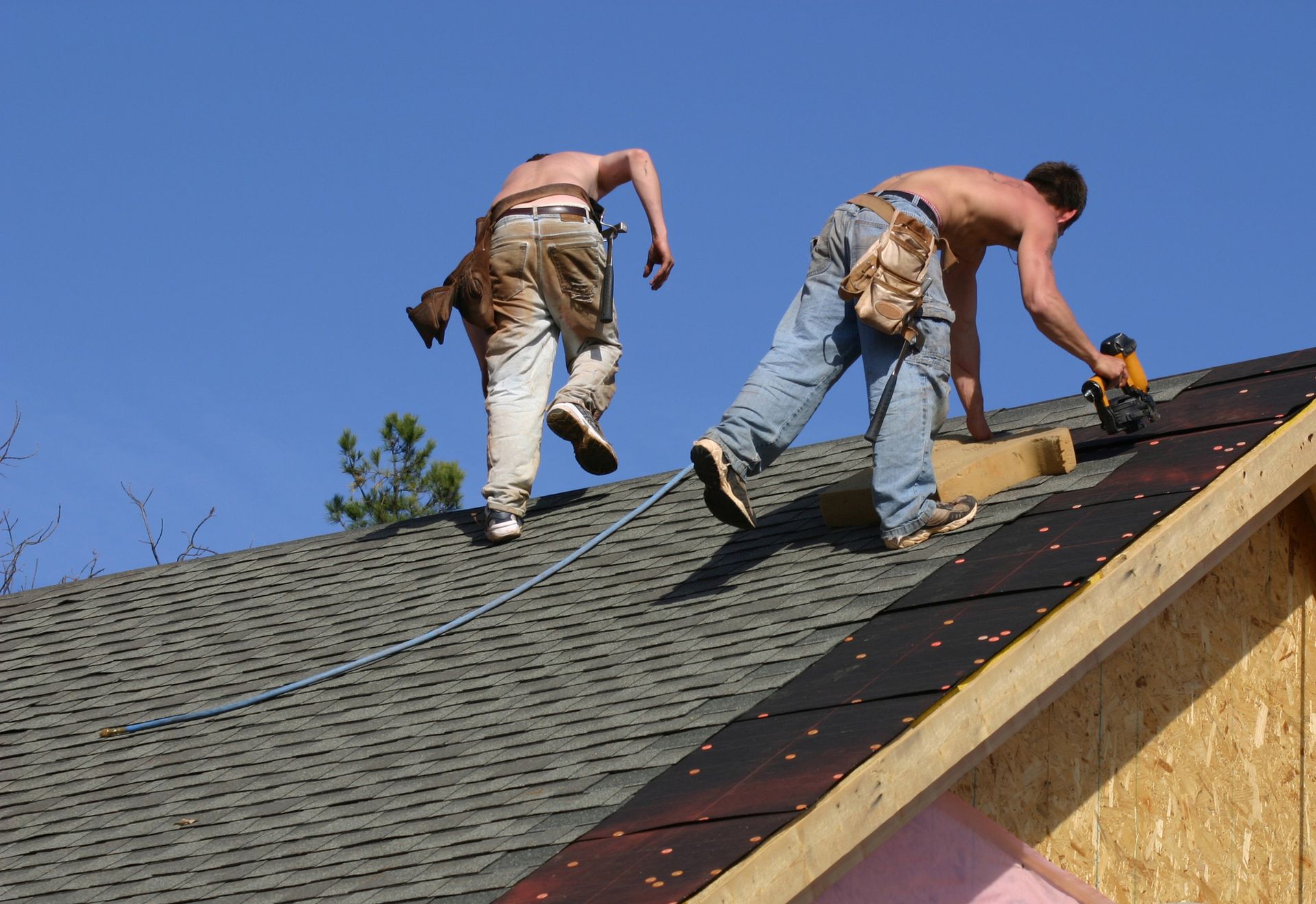 Two men in safety gear repairing a roof, showing skilled work by a roofing installation contractor.