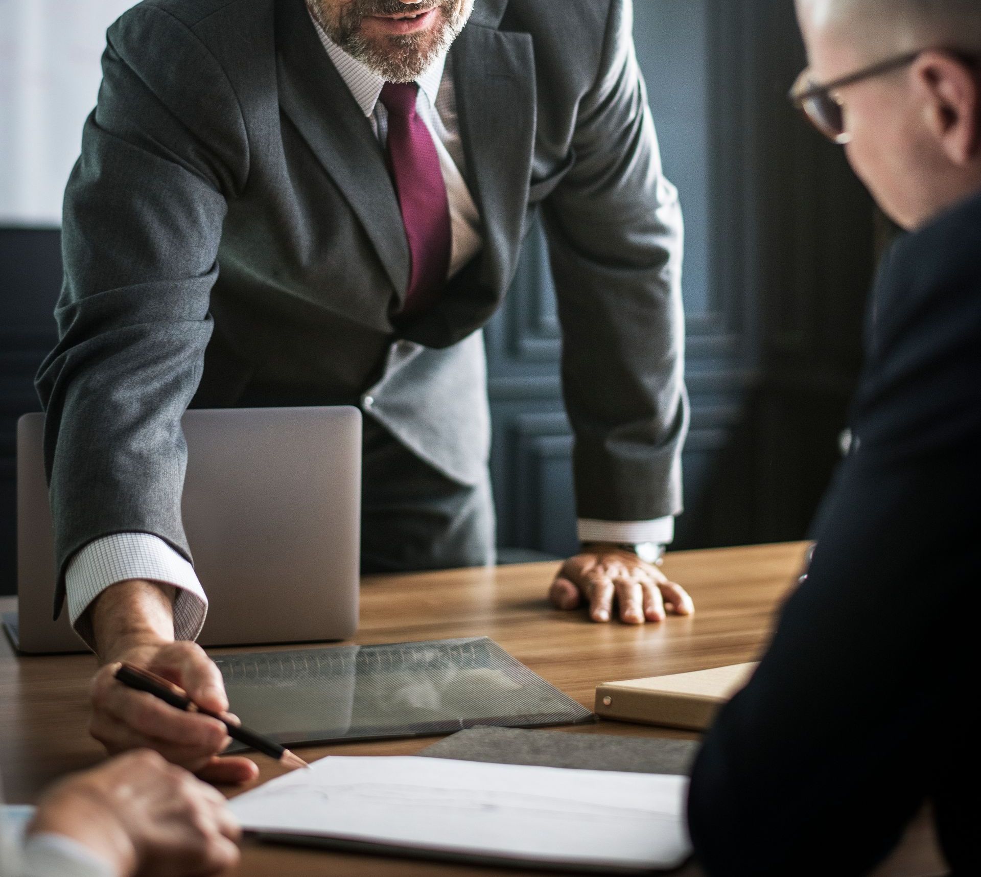 Two businesspeople leaning over a conference table, reviewing documents in an office