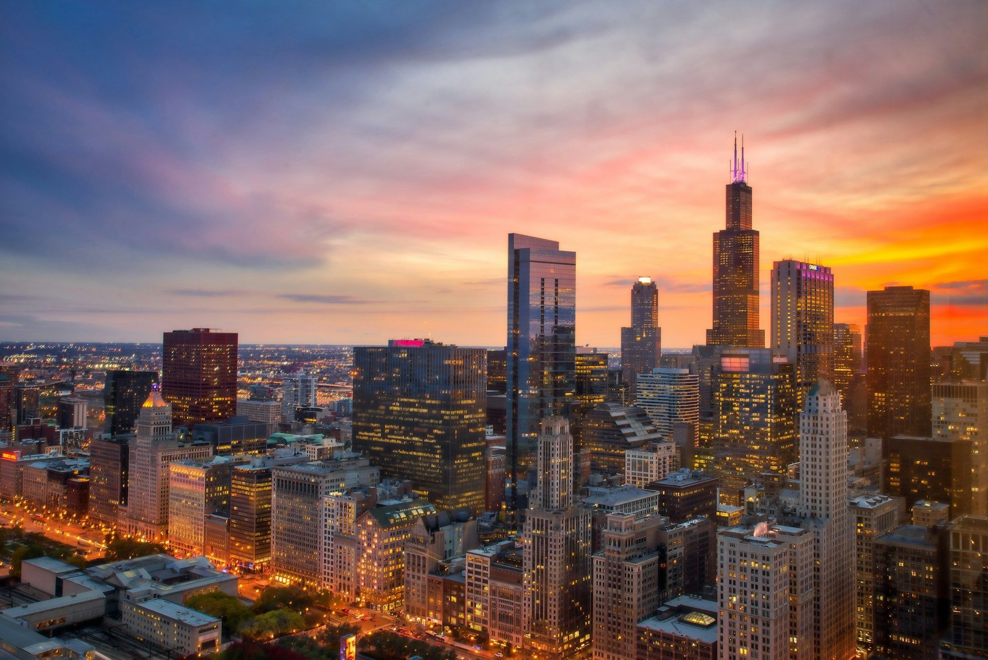 Chicago skyline at sunset with glowing skyscrapers and a colorful orange-pink sky