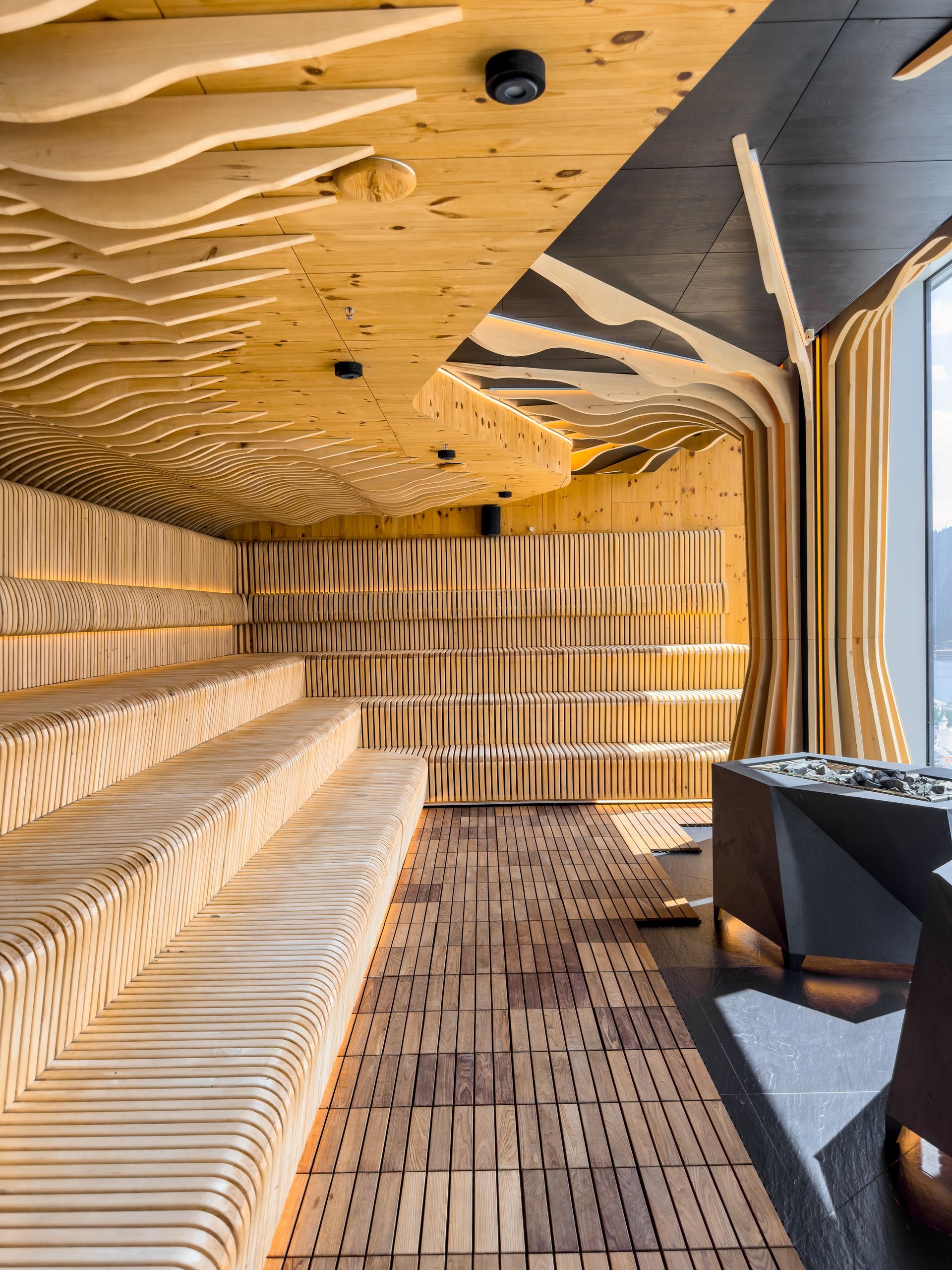 BittnerSweet Co's wood-paneled lounge with curved ceiling, striped bench seating, and large windows.