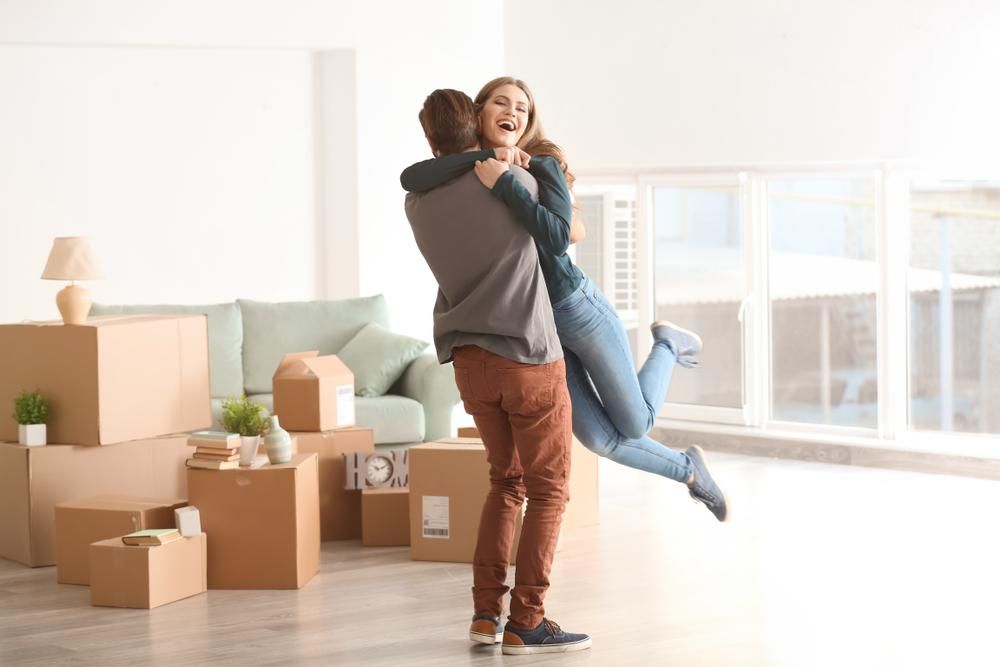 A Man Is Holding A Woman In His Arms In A Living Room — Howells & Co Legal & Conveyancing In Lake Cessnock, NSW