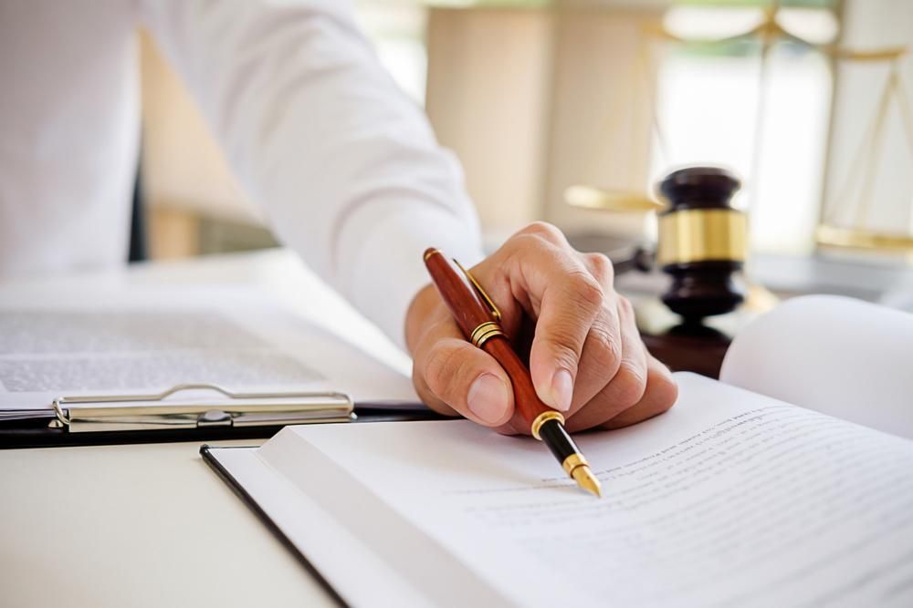A Person Is Writing On A Piece Of Paper With A Pen — Howells & Co Legal & Conveyancing In Cessnock, NSW