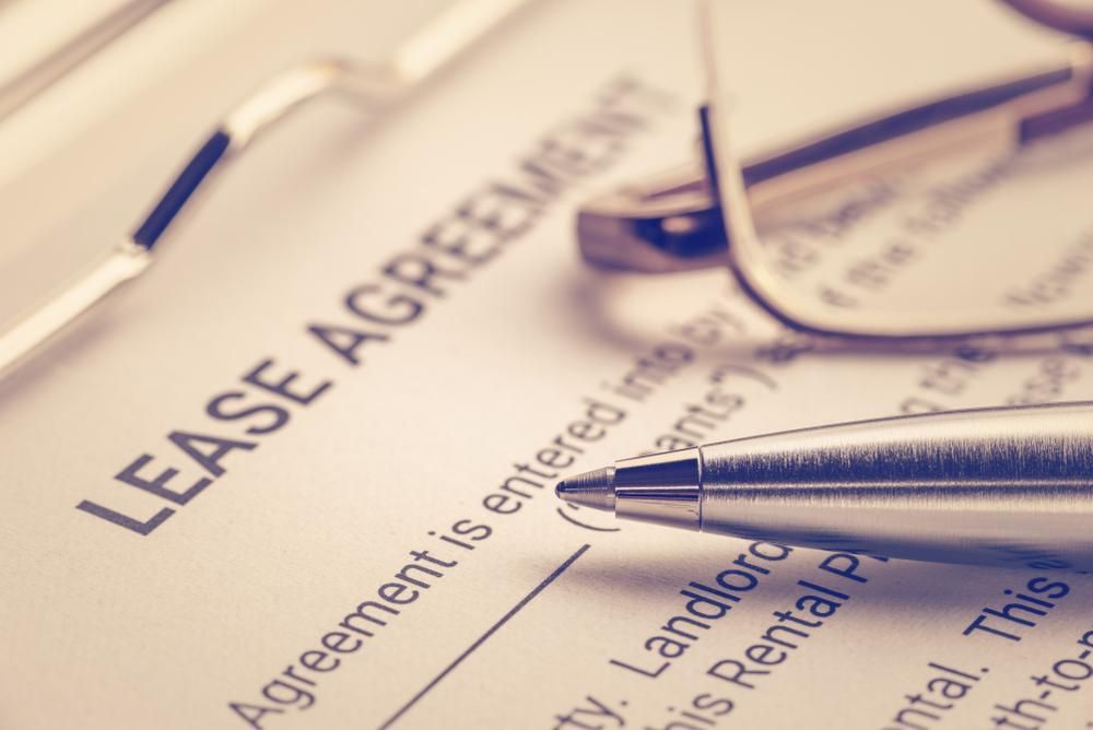 A Pen And Glasses Are On Top Of A Lease Agreement — Howells & Co Legal & Conveyancing In Cessnock, NSW