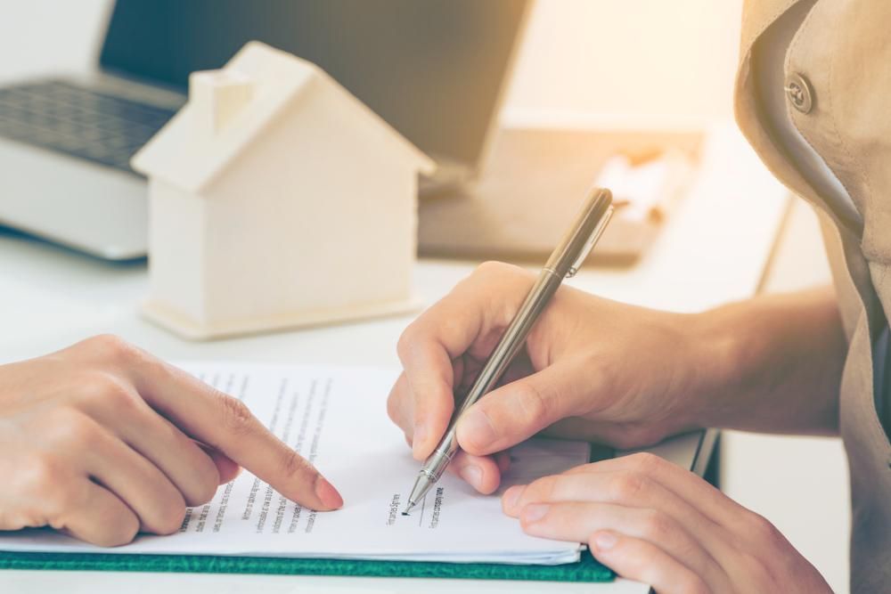 A Person Is Writing On A Piece Of Paper With A Pen — Howells & Co Legal & Conveyancing In Wollongong, NSW