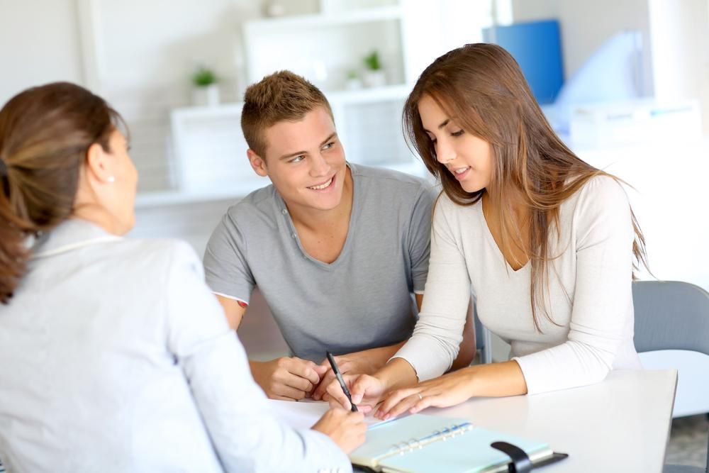 A Man And A Woman Are Sitting At A Table Talking To A Woman — Howells & Co Legal & Conveyancing In Central Coast, NSW