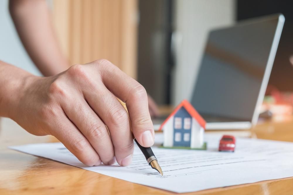 A Person Is Writing On A Piece Of Paper With A Pen — Howells & Co Legal & Conveyancing In Cessnock, NSW