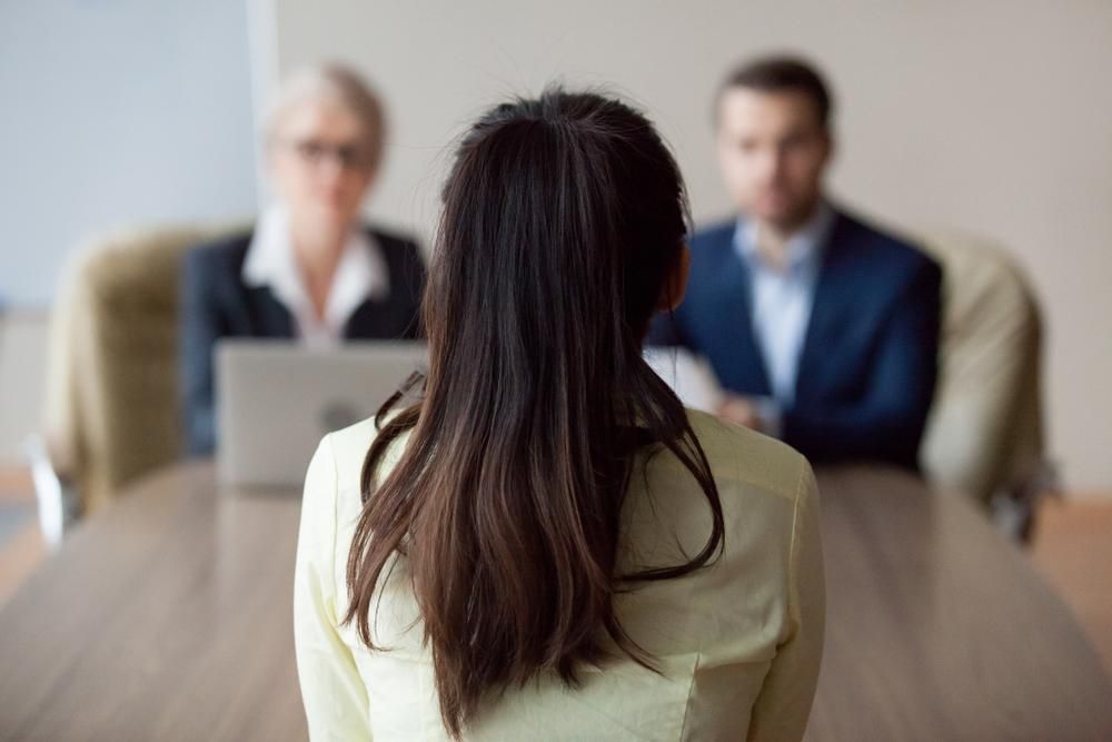 A Woman Is Sitting At A Table During A Job Interview — Howells & Co Legal & Conveyancing In Cessnock, NSW