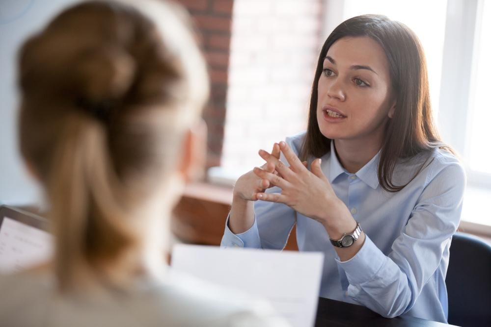 A Woman Is Sitting At A Table Talking To Another Woman — Howells & Co Legal & Conveyancing In Newcastle, NSW