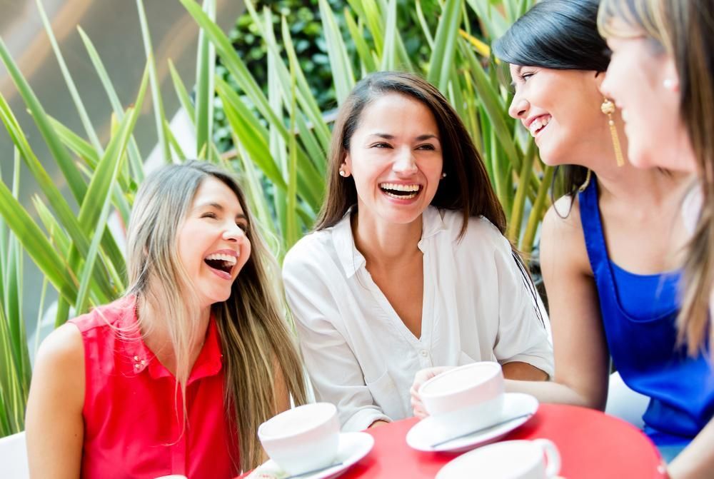 A Group Of Women Are Sitting At A Table Drinking Coffee And Laughing — Howells & Co Legal & Conveyancing In Central Coast, NSW