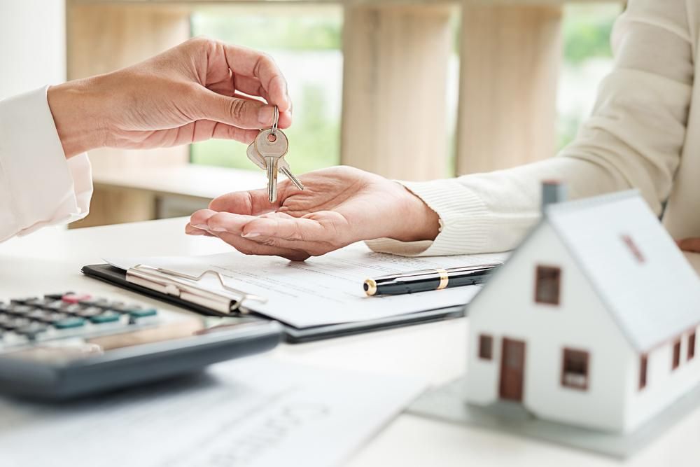 A Person Is Giving A House Key To Another Person — Howells & Co Legal & Conveyancing In Bathurst, NSW