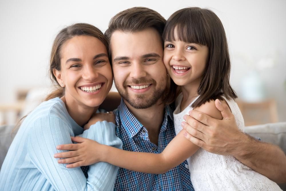 A Family Is Posing For A Picture While Sitting On A Couch — Howells & Co Legal & Conveyancing In Tamworth, NSW
