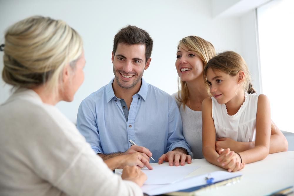 A Family Is Sitting At A Table Talking To A Woman — Howells & Co Legal & Conveyancing In Cessnock, NSW