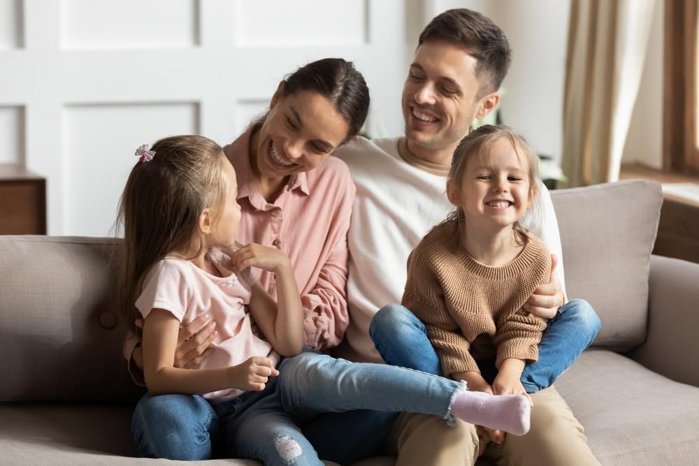 A Family Is Sitting On A Couch Together And Smiling — Howells & Co Legal & Conveyancing In Dubbo, NSW
