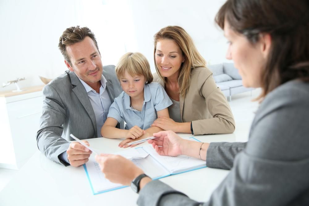 A Family Is Sitting At A Table Talking To A Woman — Howells & Co Legal & Conveyancing In Port Stephens, NSW