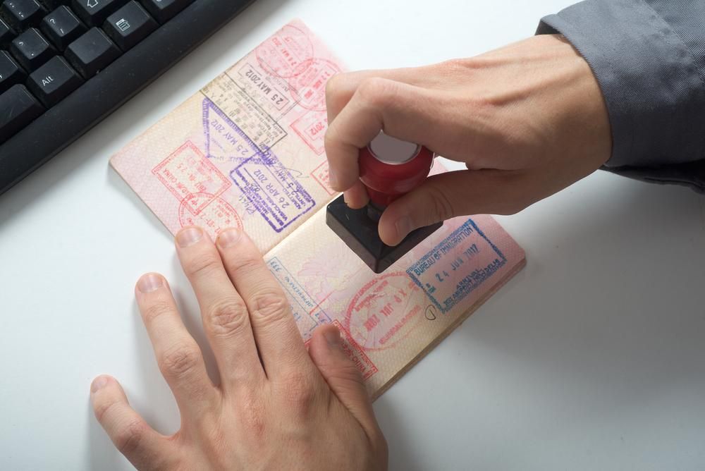 A Person Is Stamping A Passport With A Red Stam — Howells & Co Legal & Conveyancing In Cessnock, NSW