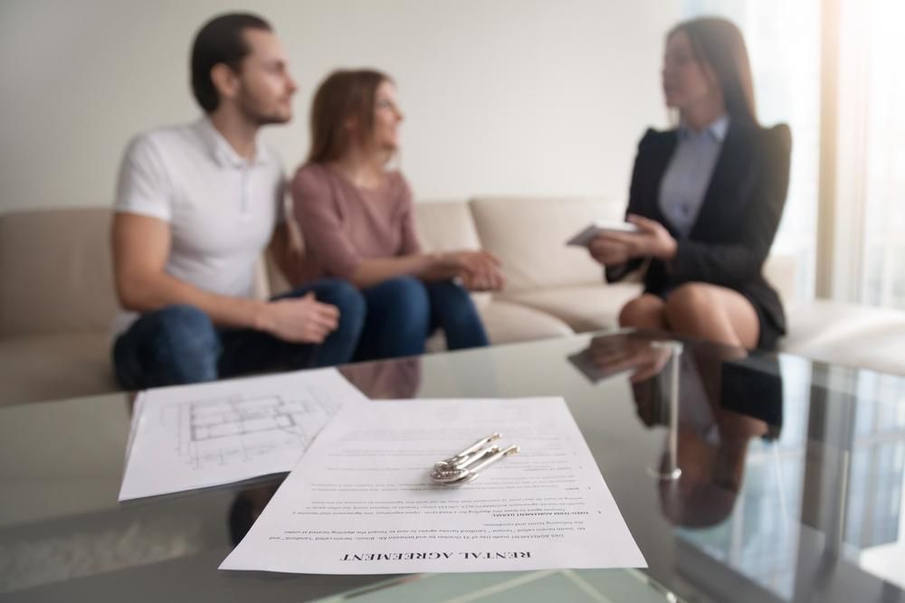 A Woman Is Sitting At A Table Talking To A Man And Woman — Howells & Co Legal & Conveyancing In Coffs Harbour, NSW