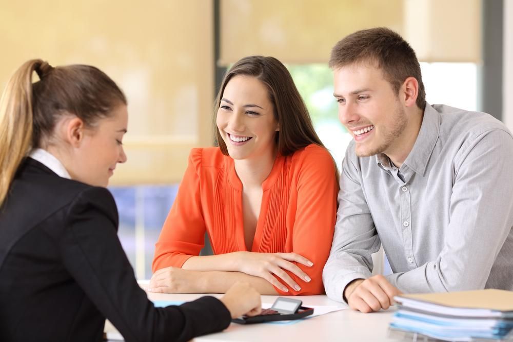 A Man And A Woman Are Sitting At A Table Talking To A Woman — Howells & Co Legal & Conveyancing In Wyong, NSW