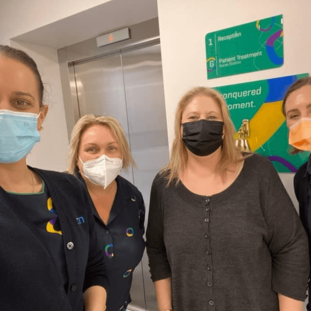 A Group Of Women Wearing Face Masks Are Standing In Front Of An Elevator — Howells & Co Legal & Conveyancing In Cessnock, NSW