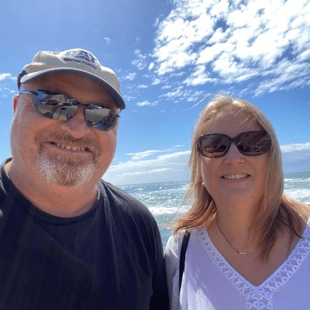 A Man And A Woman Are Posing For A Picture On The Beach — Howells & Co Legal & Conveyancing In Cessnock, NSW