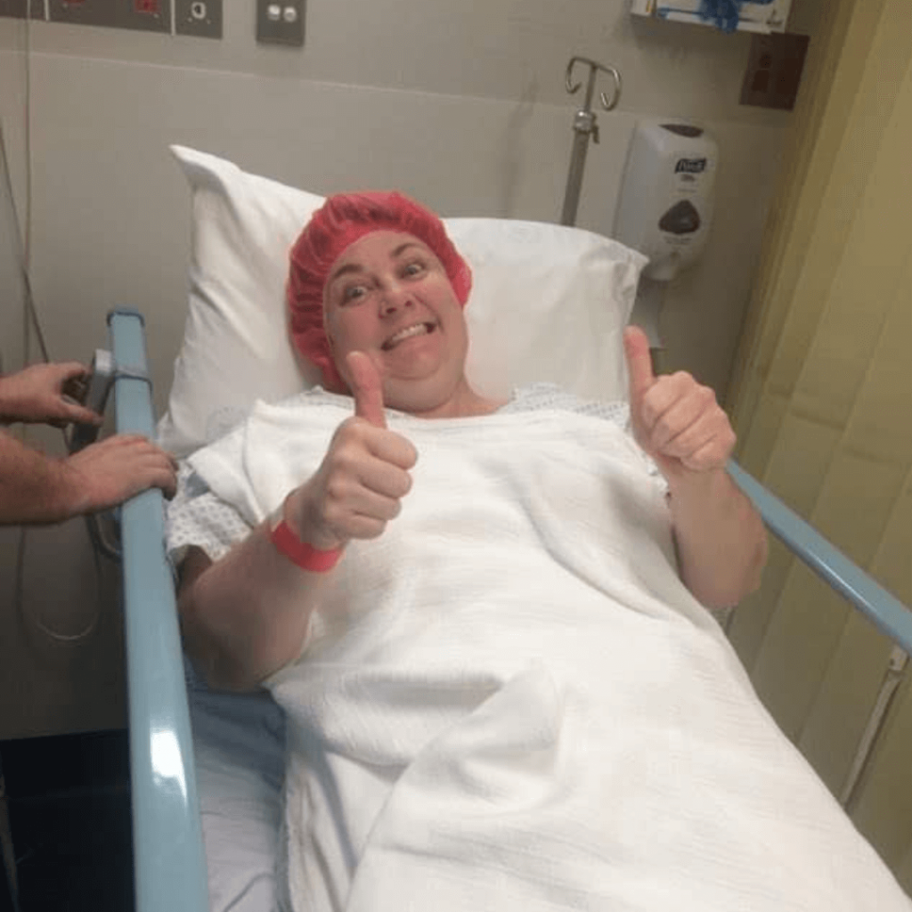 A Woman In A Hospital Bed Is Giving A Thumbs Up — Howells & Co Legal & Conveyancing In Cessnock, NSW