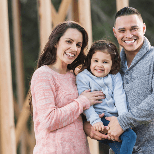 A Man And Woman Are Holding A Little Girl In Their Arms — Howells & Co Legal & Conveyancing In Cessnock, NSW