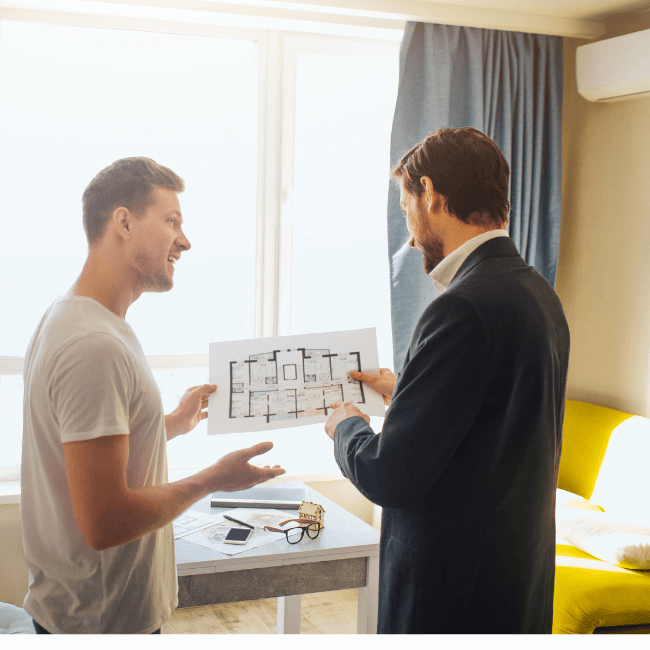 Two Men Are Looking At A Blueprint Of A House — Howells & Co Legal & Conveyancing In Cessnock, NSW