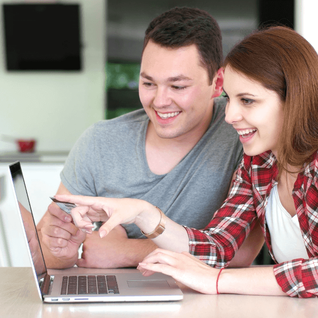 A Man And A Woman Are Looking At A Laptop Together — Howells & Co Legal & Conveyancing In Cessnock, NSW