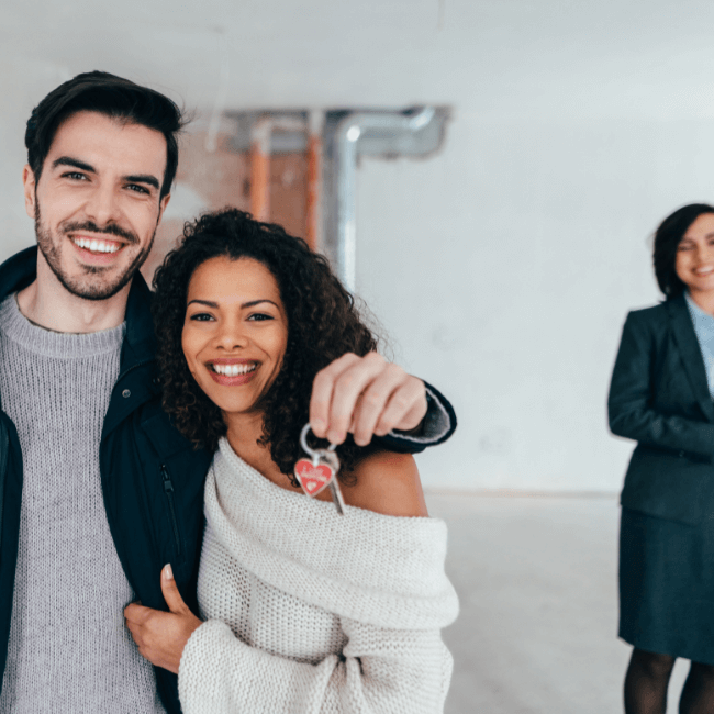 A Man And Woman Are Posing For A Picture While The Woman Is Holding A Key — Howells & Co Legal & Conveyancing In Cessnock, NSW