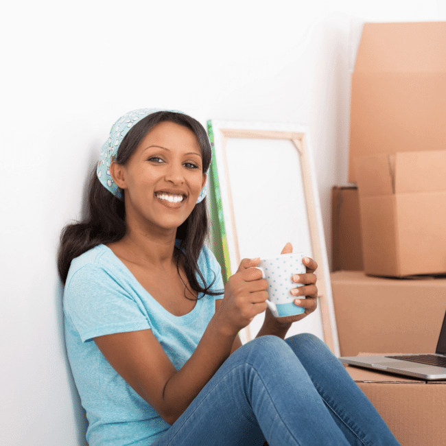 A Woman Is Sitting On The Floor Holding A Cup Of Coffee — Howells & Co Legal & Conveyancing In Lake Cessnock, NSW