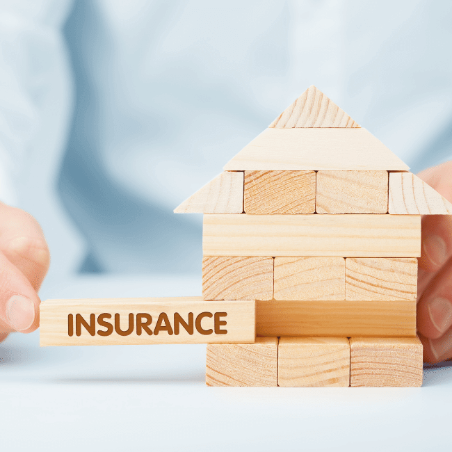 A Person Is Holding A Wooden House With A Sign That Says Insurance  — Howells & Co Legal & Conveyancing In Lake Cessnock, NSW