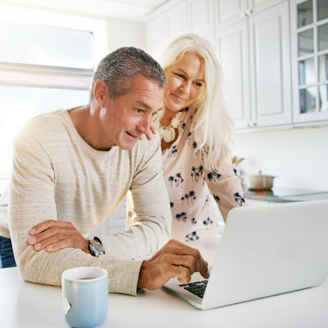A Man And A Woman Are Looking At A Laptop Computer — Howells & Co Legal & Conveyancing In Cessnock, NSW