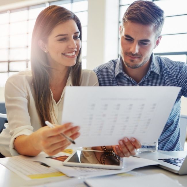 A Man And A Woman Are Looking At A Piece Of Paper — Howells & Co Legal & Conveyancing In Cessnock, NSW