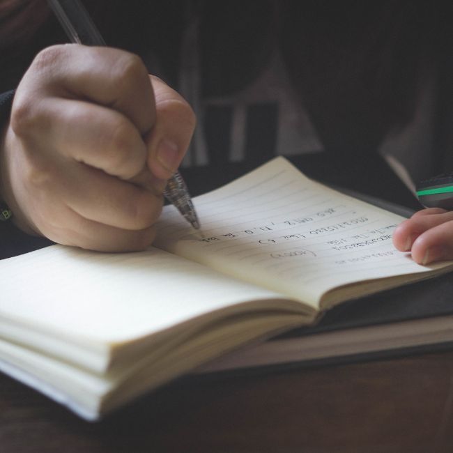 A Person Is Writing In A Notebook With A Pen — Howells & Co Legal & Conveyancing In Cessnock, NSW