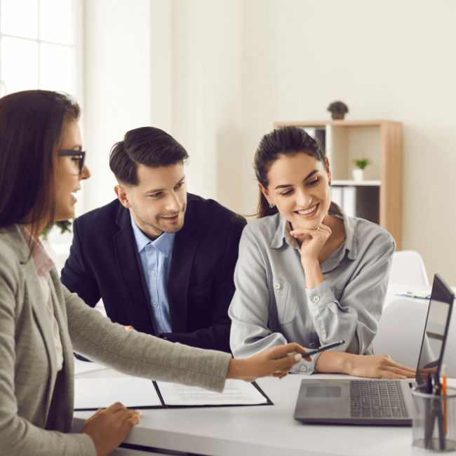 A Group Of People Are Sitting At A Table Looking At A Laptop — Howells & Co Legal & Conveyancing In Cessnock, NSW