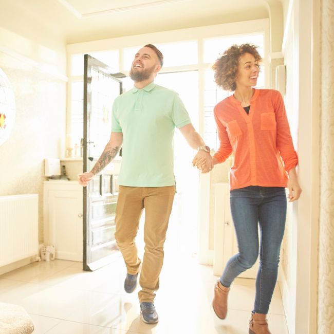 A Man And A Woman Are Walking Down A Hallway Holding Hands — Howells & Co Legal & Conveyancing In Cessnock, NSW