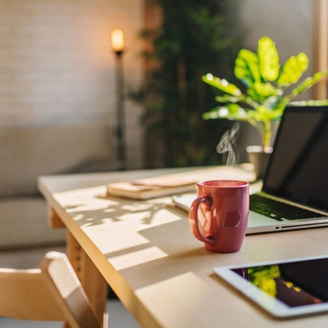 A Cup Of Coffee Is Sitting On A Desk Next To A Laptop And A Tablet — Howells & Co Legal & Conveyancing In Cessnock, NSW