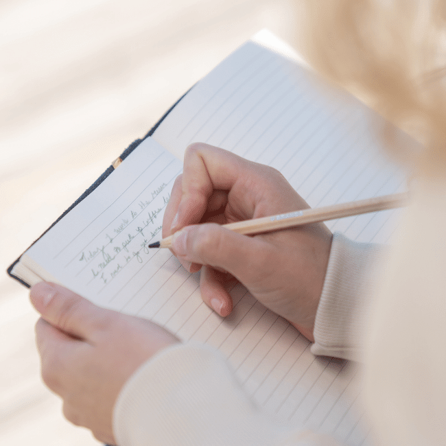 A Person Is Writing In A Notebook With A Pencil — Howells & Co Legal & Conveyancing In Cessnock, NSW