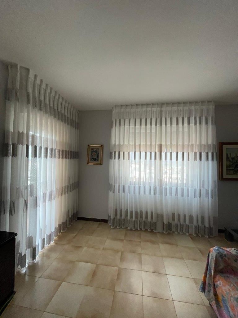 Un soggiorno con un divano, tende e un quadro alla parete.