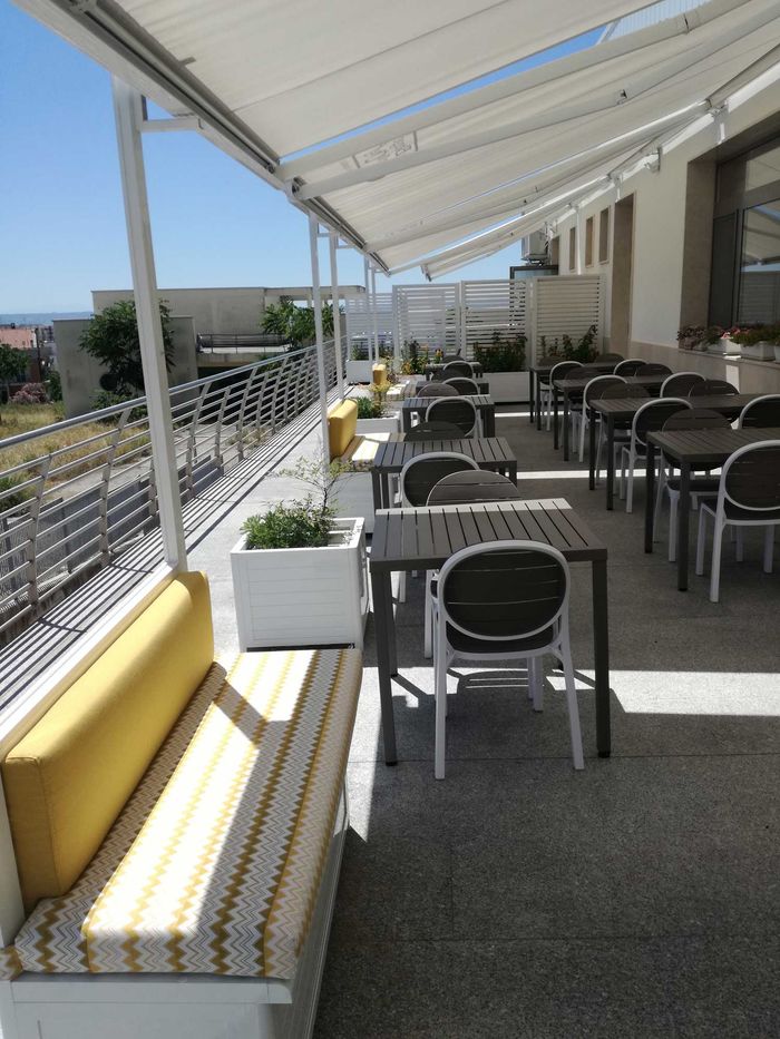 Un patio con tavoli e sedie sotto una tenda da sole