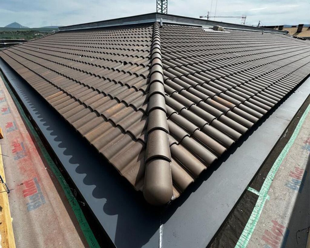Worker repairing a damaged rooftop beside brick chimneys under a blue sky
