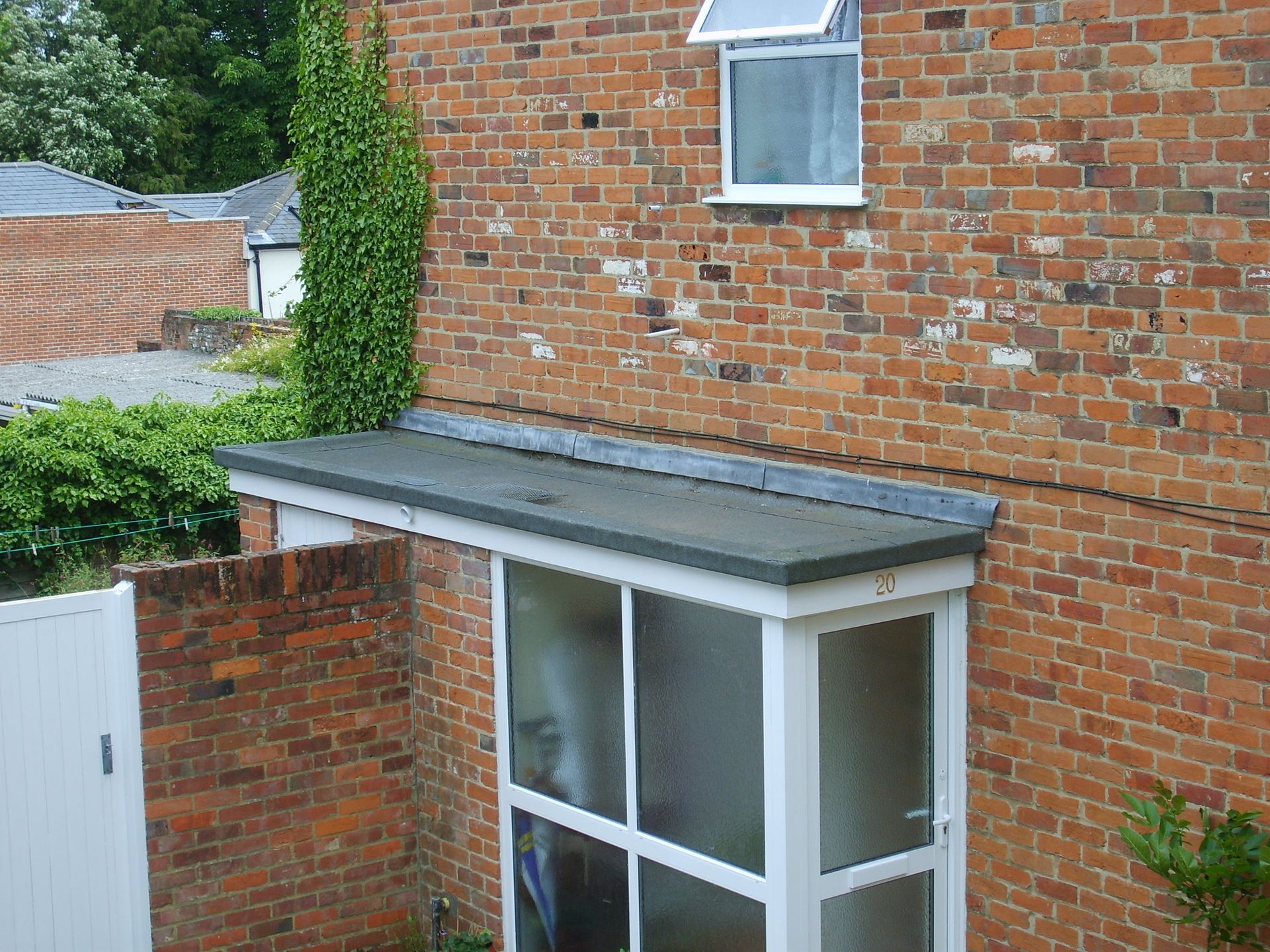 Brick building with a white-framed porch with a flat roof. A small window is above the porch.