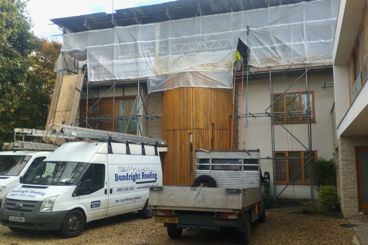 Construction site with scaffolding and tarps on a two-story building.
