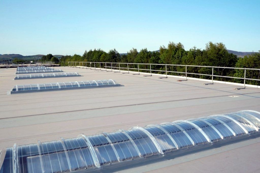 A flat, white industrial roof with several arched skylights.